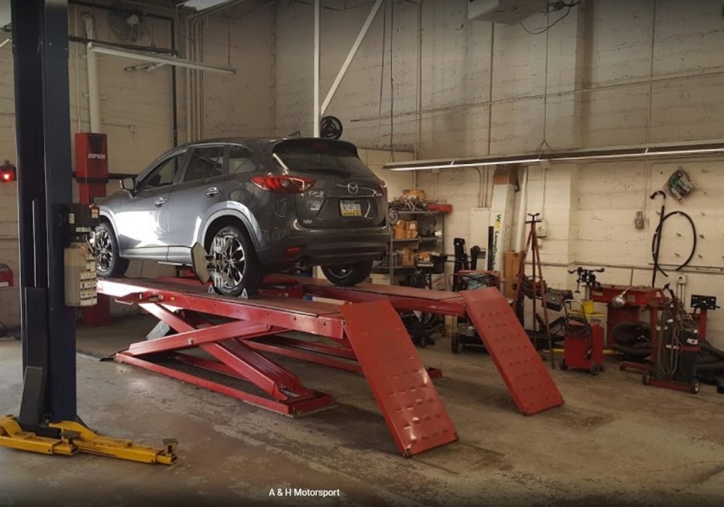 Car on hydraulic lift in auto repair shop for maintenance service in in Warminster PA